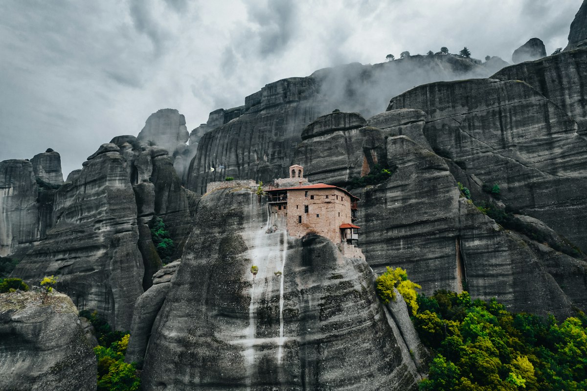 A small monastery on a rock pillar among cloud-wrapped cliffs at Meteora