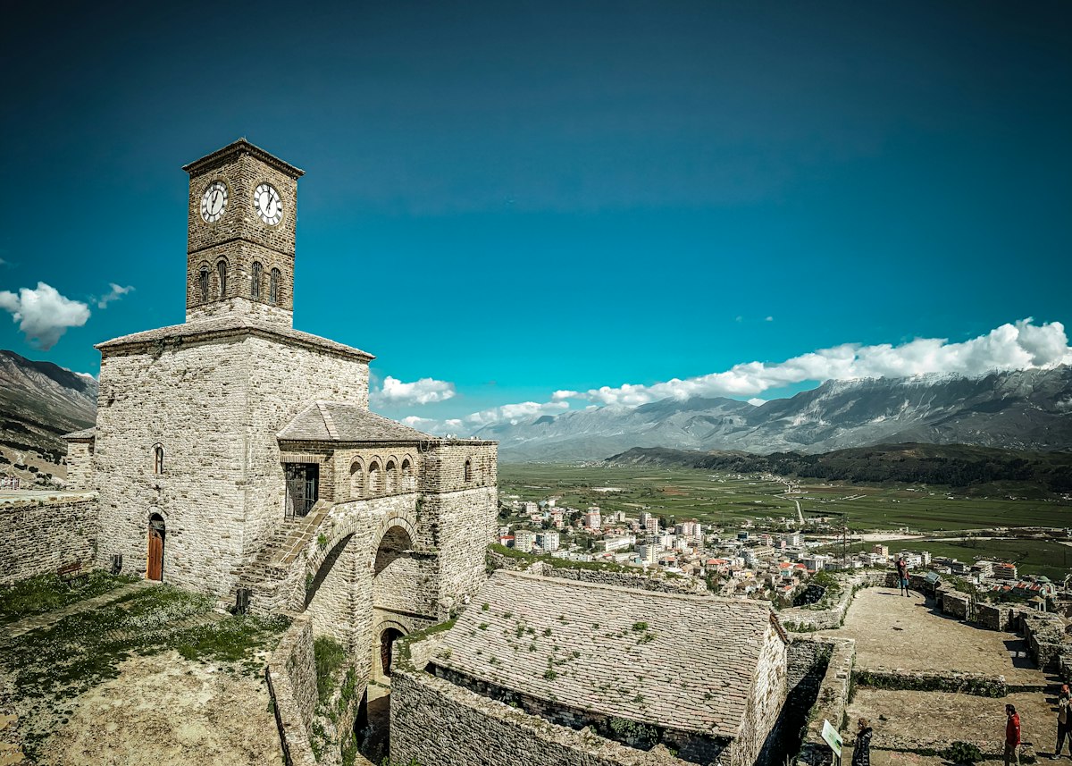 The clock tower of Gjirokastra castle with the town and a mountain range beyond